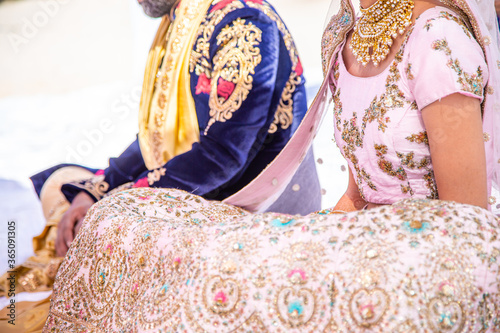 Sikh bride and groom next to each other during marriage ceremony in traditional wedding attire © Nicholas