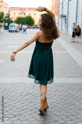 Girl in a green dress posing holding her hand up. Portrays a dance