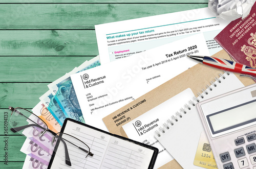 English form sa100 Tax return by HM revenue and customs lies on table with office items. HMRC paperwork and tax paying process in United Kingdom photo