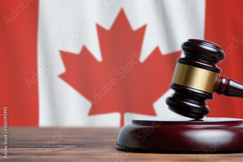 Justice and court concept in Canada. Judge hammer on a flag background