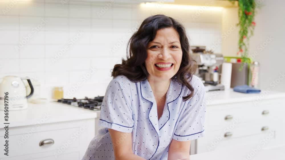 Portrait of smiling mature Hispanic woman wearing pyjamas spending morning at home in kitchen - shot in slow motion Portrait of smiling mature Hispanic woman wearing pyjamas spending morning at home in kitchen - shot in slow motion