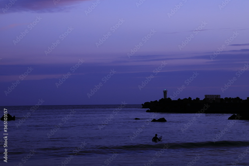 日没後の海に残るサーファー