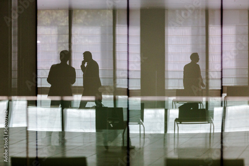 silhouettes of businessmen in building lobby as seen through glass wall at workplace photo