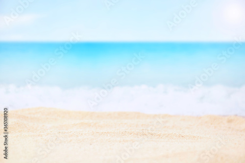 Blurred blue sea and sand beach, selective focus on sand for product display
