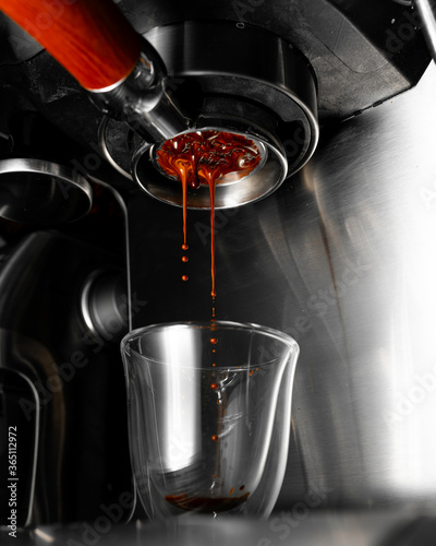 Espresso dripping from a machine into a clear shot glass