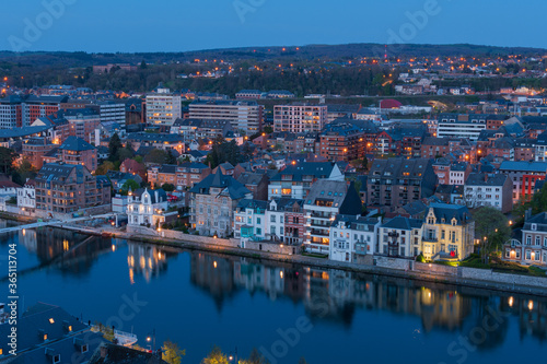View of Namur and Jambes at sunset when the lights switch on and the reflection of the houses on the Meuse river.