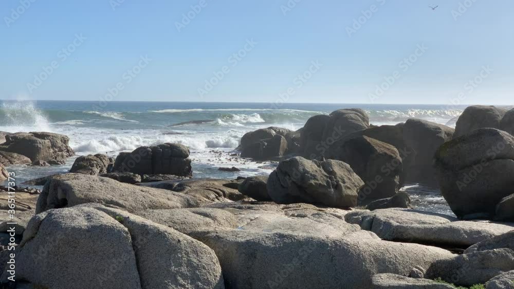 Granite boulders on the rocky Atlantic shoreline being crashed by huge waves of the deep blue ocean and blue skies to the horizon Granite boulders on the rocky Atlantic shoreline being crashed by huge waves of the deep blue ocean and blue skies to the horizon