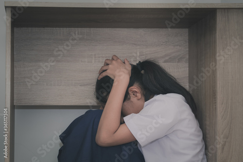 Asian young girl in a school uniform hides under the desk when an earthquake occurs with concept
