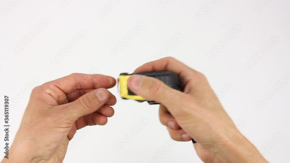 human hands pull the measuring tape out of tape measure and measure diagonal dimensions, then removes it, close up view on white background human hands pull the measuring tape out of tape measure and measure diagonal dimensions, then removes it, close up view on white background