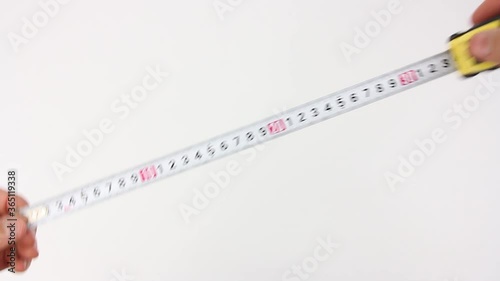 human hands pull the measuring tape out of tape measure and measure the dimensions, length width height and diagonal, then removes it, close up view on white background