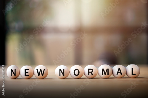 new normal, word on wooden circle on  laptop, affectation after covid-19 pandemic