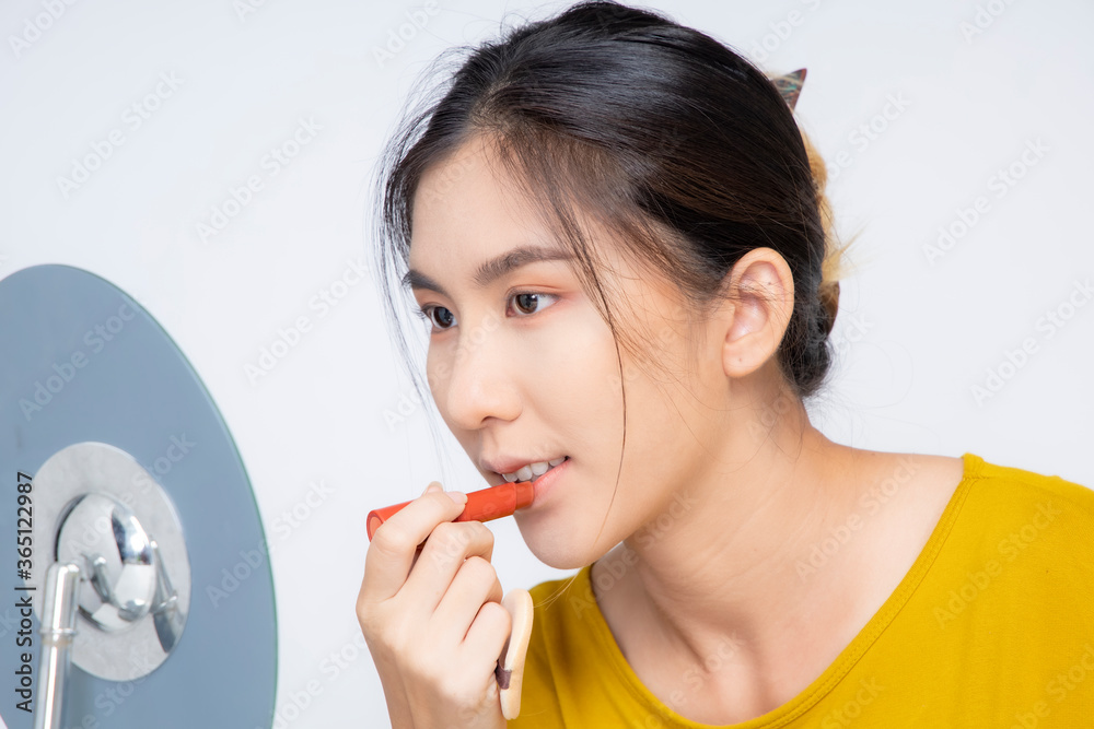 An Asian blogger beauty blogger shooting a video of herself wearing an orange lipstick in a studio. An Asian blogger beauty blogger shooting a video of herself wearing an orange lipstick in a studio.