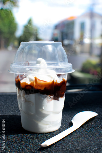 soft serve chocolate ice-cream sundae, sweets in a plastic cup with a plastic spoon from a fast-food drive-through take home restaurant in the car. photo