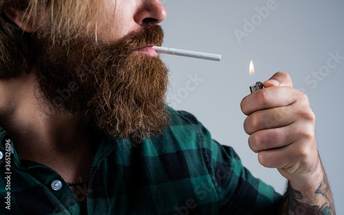 lightng the cigarette. bearded man. smoking cigarette habit. brutal hipster with moustache. fashion model in casual clothes. male beauty standard. looking so trendy. Confident and handsome brutal man photo
