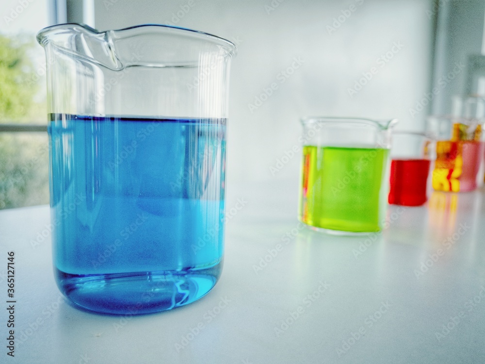 Close up Science glass flask with blue and other colors in water in chemistry research laboratory. Close up Science glass flask with blue and other colors in water in chemistry research laboratory.