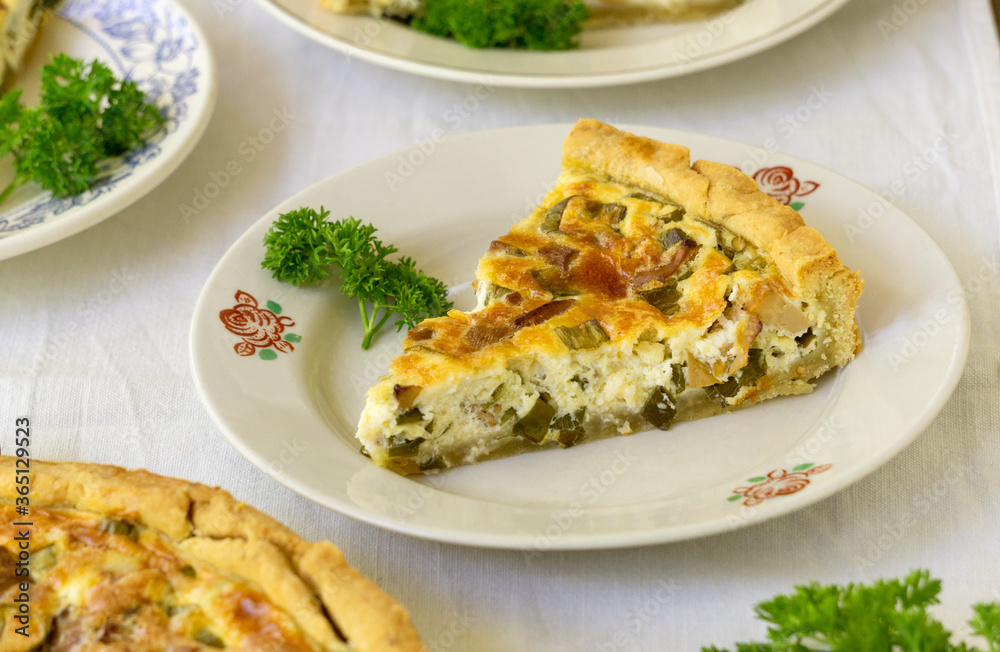 Piece of quiche with chanterelles, herbs and cheese on a white plate