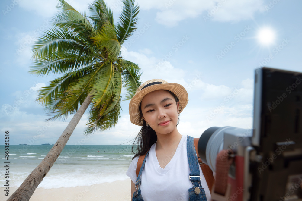 Asian girl selfie by digital camera with beach and coconut background