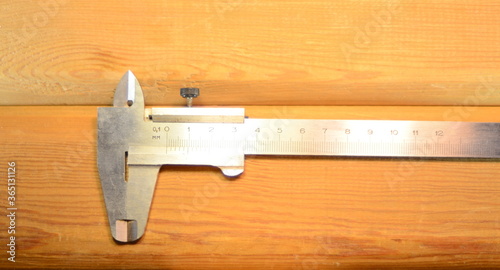 steel caliper on a light background of wooden boards