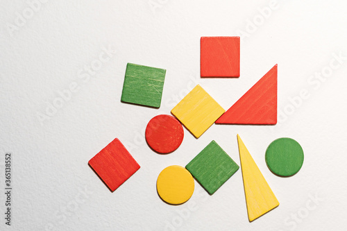 Different colorful shapes wooden on white background. Geometric shapes red, green, yellow colors, top view. Concept of geometry. Copy space. Children educational logical task. Flat lay.