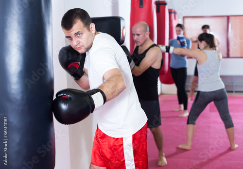 .Male athlete beating boxing bag training in boxing gloves