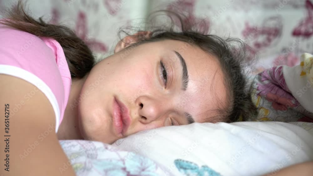 sleeping teenager girl with long hair wakes up opens and closes eyes