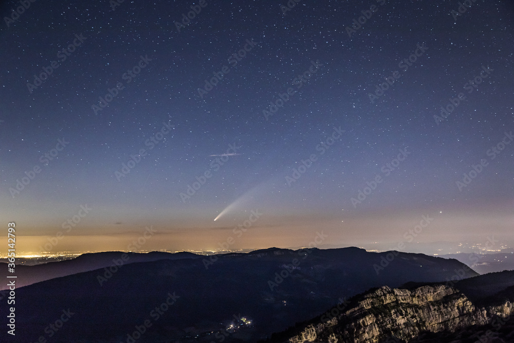 Neowise comet over mountain and city in vercors moountain range