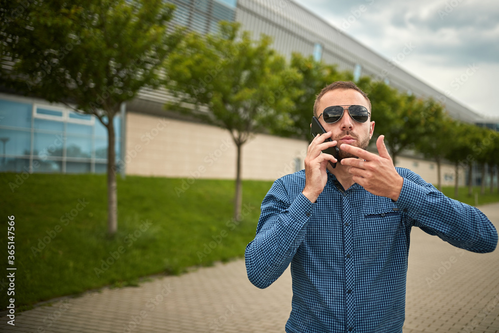 Man arguing over smart phone. Ouch someone is mad at me. Portrait of intense displeased young handsome male scolded by interlocutor via telephone holding smartphone. Furious businessman talking. Man arguing over smart phone. Ouch someone is mad at me. Portrait of intense displeased young handsome male scolded by interlocutor via telephone holding smartphone. Furious businessman talking.