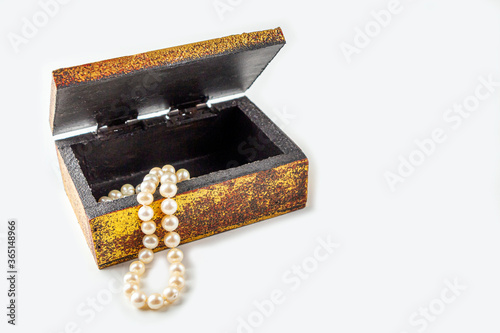 Pearl necklace, beads in antique metallic vintage casket on white background. Oldfashioned decoration from grandma's jewelry box. Copy space, close-up