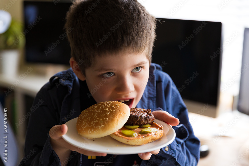 Boy holding a classic american hamburger on a plate Boy holding a classic american hamburger on a plate