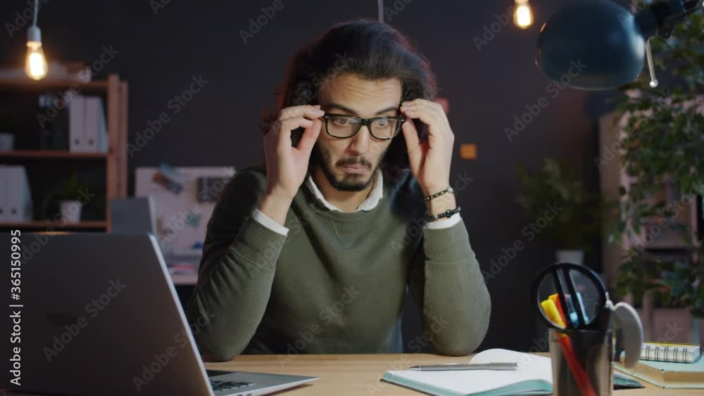 Arab man is sleeping in office at desk then waking up and working with laptop late in the evening. Overworked people, technology and business concept. Arab man is sleeping in office at desk then waking up and working with laptop late in the evening. Overworked people, technology and business concept.