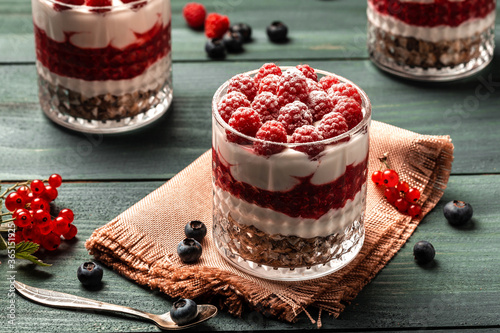 Healthy raspberry fruit dessert with skyr yogurt, granola layered in jar surrounded by ingredients, Vegetarian breakfast, fresh raspberries and blueberries yoghurt