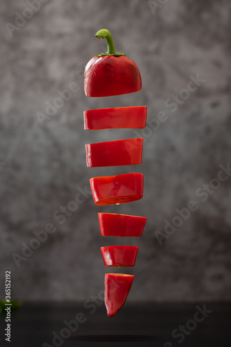 Sliced capia pepper floating on dark background