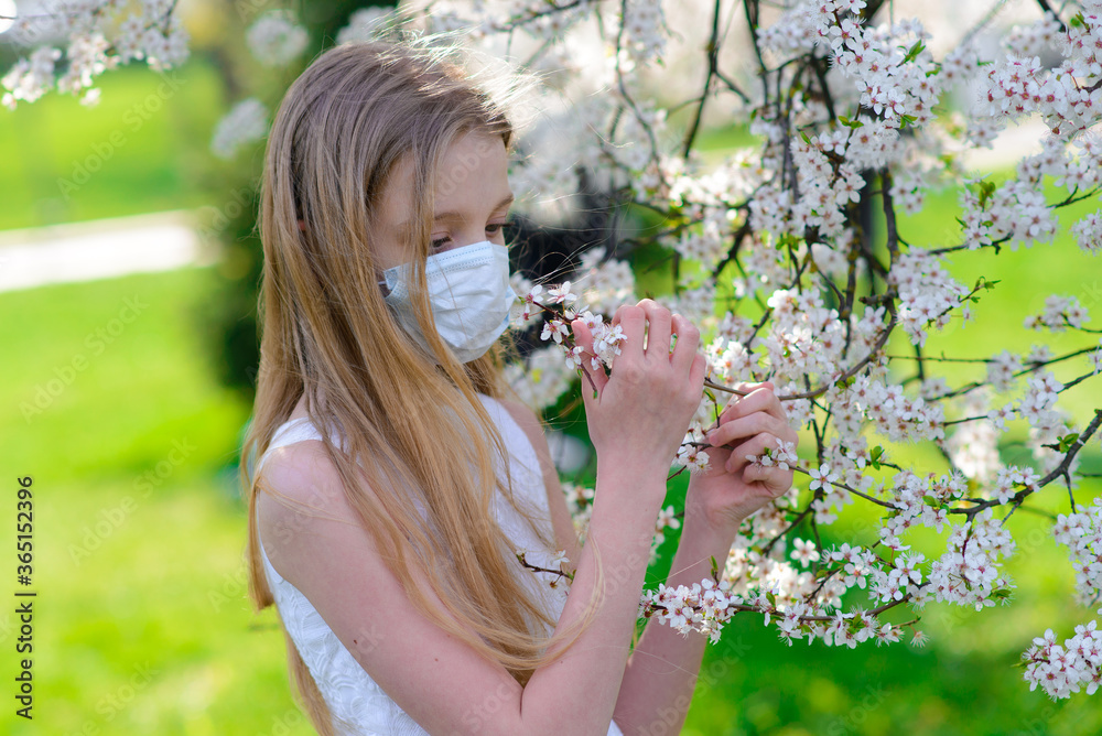 Teenager girl in medical mask in spring flowering garden. Concept of social distance and prevention of coronavirus. Teenager girl in medical mask in spring flowering garden. Concept of social distance and prevention of coronavirus.