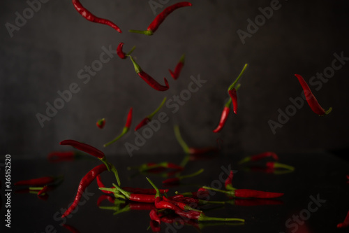 Floating red hot pepper, chilli peper dropind down at dark background
