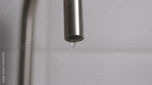 Close shot of dripping faucet on a white background