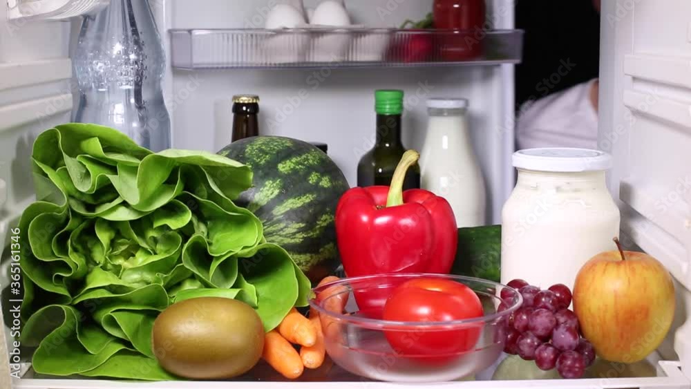 Hand of a man grabbing a tomato from the fridge Hand of a man grabbing a tomato from the fridge
