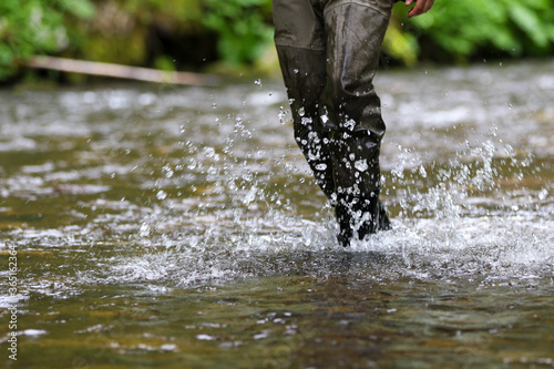 Fisherman wades the river in high boots
