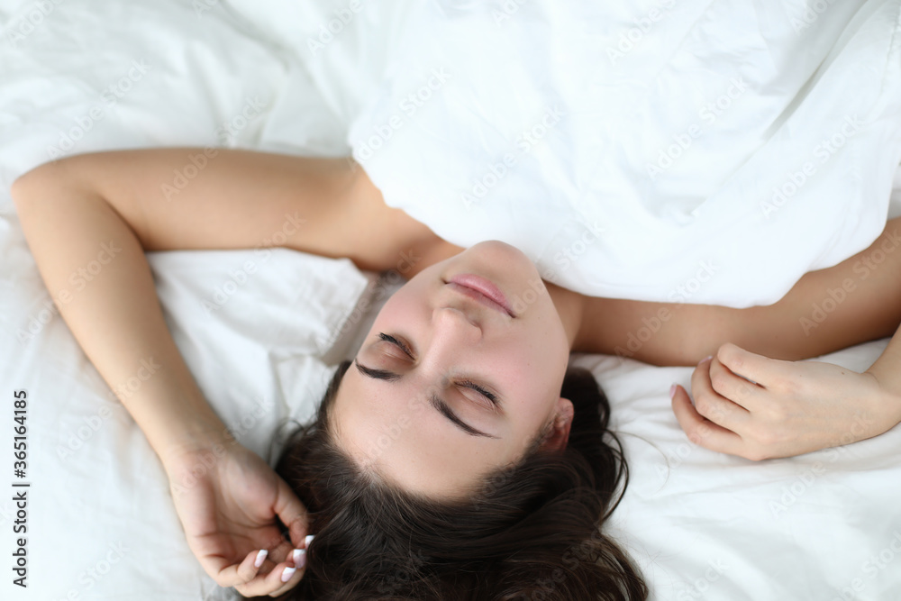 Top view of lovely young woman with beautiful brunette hair laying on white bedding. Pretty female resting at home. Comfy pink blouse for sleep. Good morning and well rested lady Top view of lovely young woman with beautiful brunette hair laying on white bedding. Pretty female resting at home. Comfy pink blouse for sleep. Good morning and well rested lady
