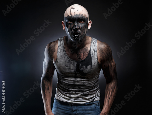 Photo of dirty mad man with black muck in the mouth