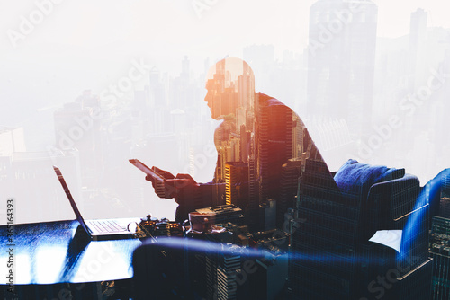 Double exposure silhouette of successful businessman is working in office company with net-book and touch pad. Thoughtful entrepreneur is using digital tablet and laptop computer for finance analyze