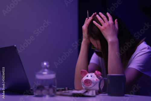 Close-up of glass container with coins. Depressed woman calculating family financial situation. Lady closing face with hand. Saving up for future. Money and investment concept photo