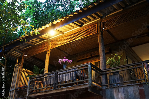 Exterior balcony architecture and terrace decoration of old antique wooden building among green natural park decorated with dining table set and flower vase