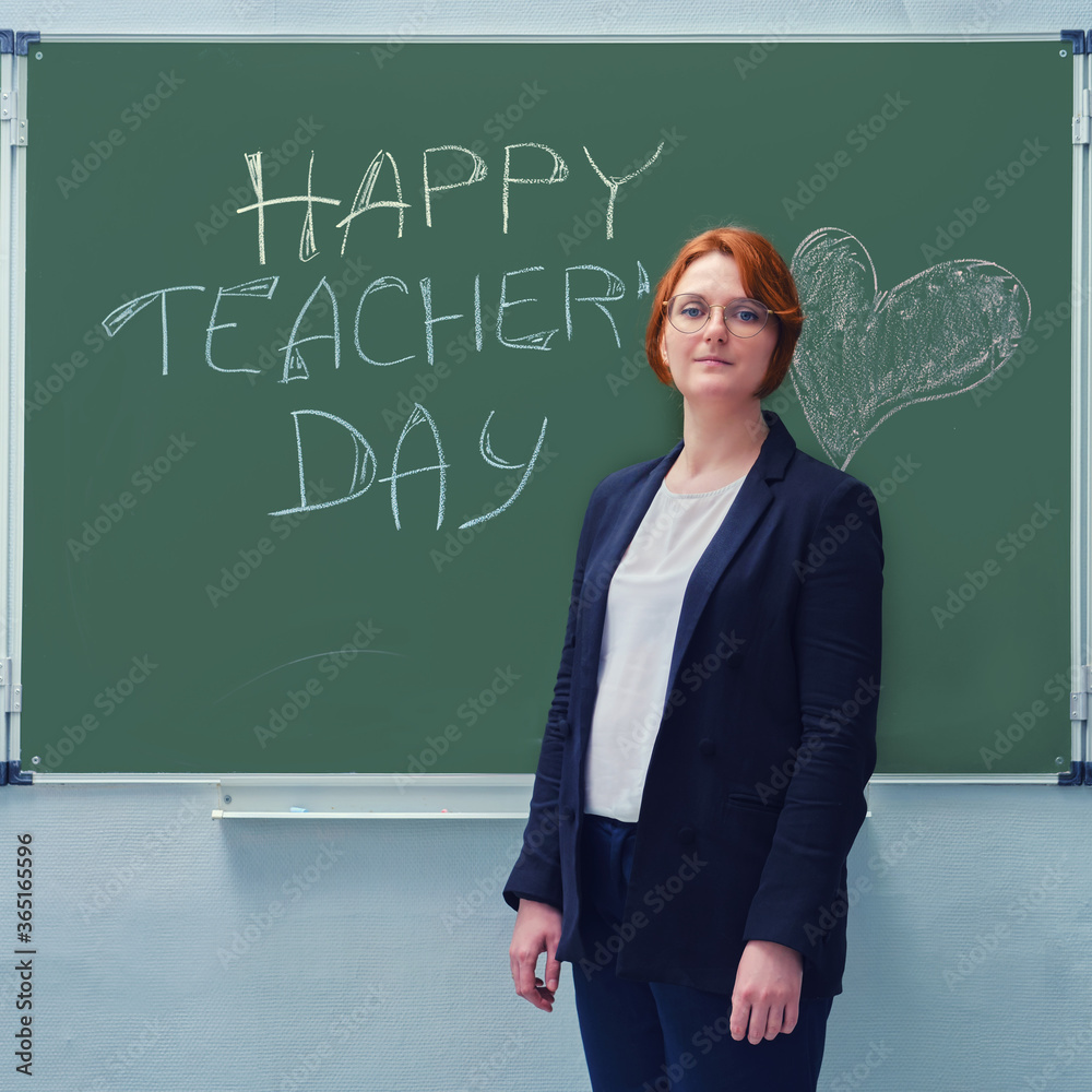 Portrait of a young teacher near the blackboard with a congratulation. The face of a red-haired woman and the text 