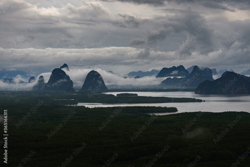 The scenery of the archipelago of the Sametnangshe island in the morning with the mist and fog over the summit in Phang Nga province, Thailand.