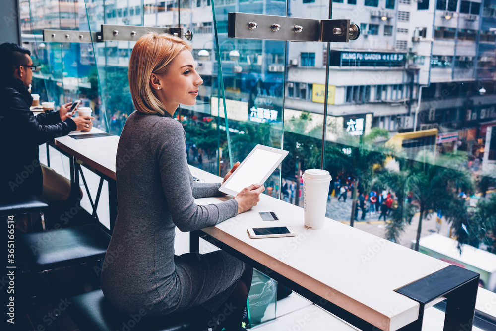 Φωτογραφία Attractive cheerful young woman enjoying cityscape looking out of window while i