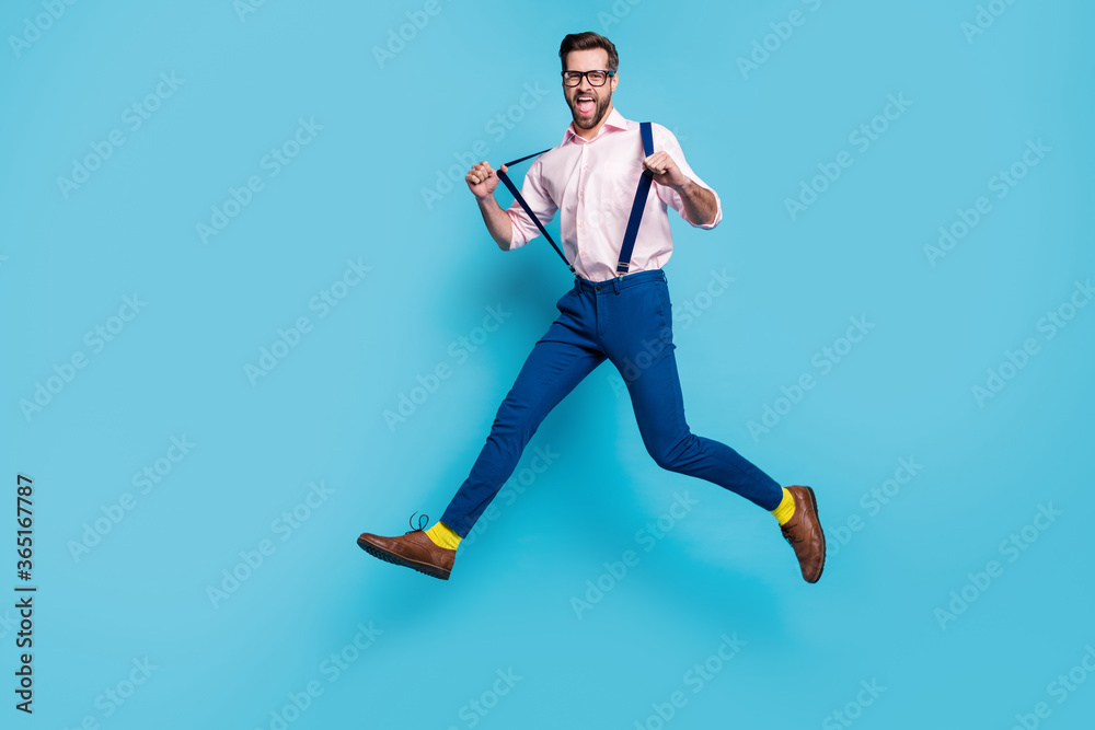 Full length profile photo of handsome business man jump high shopping center running crazy addicted shopaholic wear specs shirt suspenders pants boots isolated blue color background