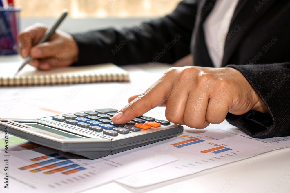 Close-up of women using calculators to create accounting reports by the window in their own homes, cost calculation concepts, and work at home concepts. Close-up of women using calculators to create accounting reports by the window in their own homes, cost calculation concepts, and work at home concepts.