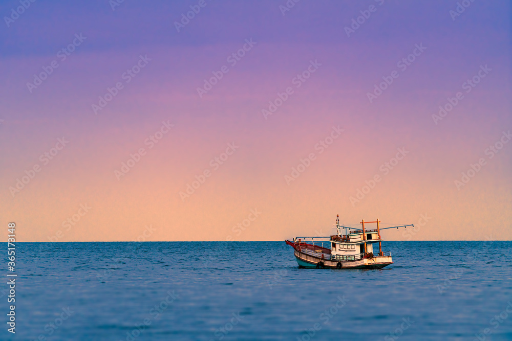 Beautiful scene of Asian fishing boat in late sunset, one fishing boat and beautiful purple and yellow light on sky, water front blurred.