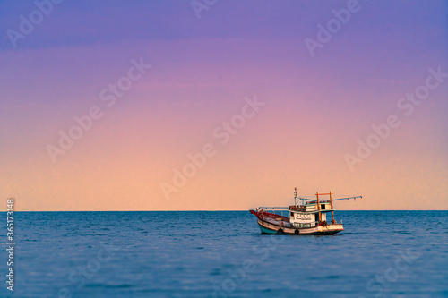 Beautiful scene of Asian fishing boat in late sunset, one fishing boat and beautiful purple and yellow light on sky, water front blurred.
