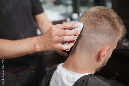 Rear view close up of a barber shaving back of the head of his client © Ihor